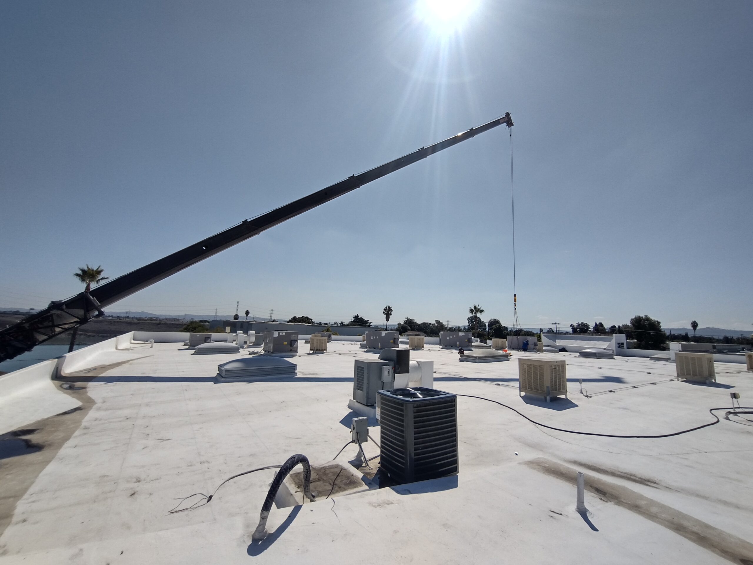 Commercial HVAC units on rooftop with crane